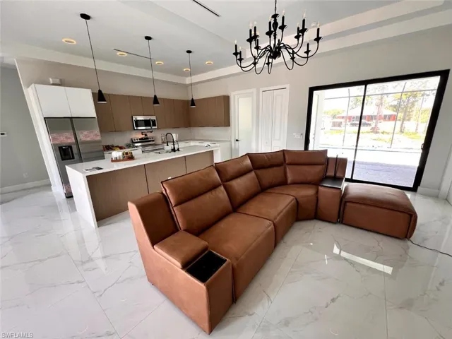 Open-concept living area featuring a modern kitchen with a large island, stainless steel appliances, and wood-finish cabinetry