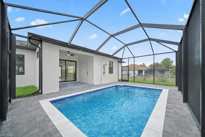 Swimming pool with a sunroom, a patio area, and glass enclosure