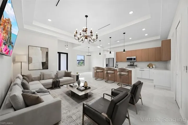 Living area featuring hanging lights, light marble finish floors, and a raised ceiling