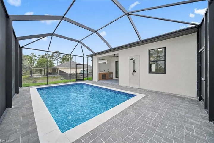 Swimming pool with a sunroom, a patio area, a lanai, and exterior kitchen