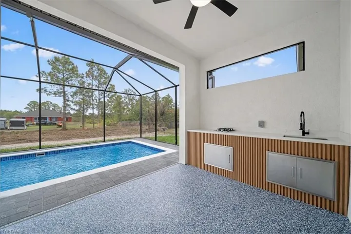 Outdoor pool featuring a patio area, a sunroom, and glass enclosure