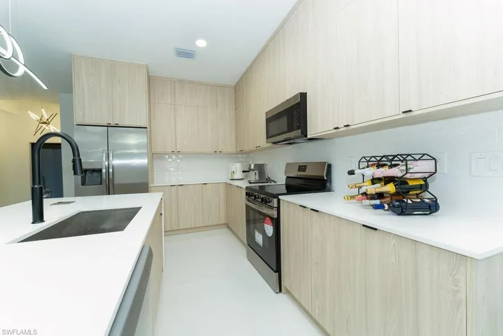 Kitchen with modern cabinets, light brown cabinets, stainless steel appliances, decorative backsplash, and recessed lighting