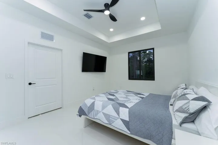 Bedroom with a raised ceiling, recessed lighting, ceiling fan, and light tile patterned flooring