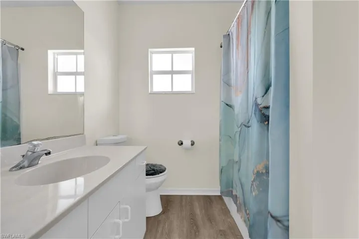 Full bath with light wood-style flooring, vanity, and curtained shower