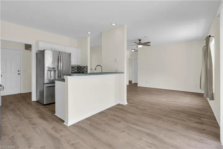 Kitchen with stainless steel fridge, tasteful backsplash, recessed lighting, light wood-style floors, and open floor plan
