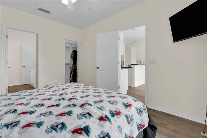Bedroom featuring dark wood-style flooring, a ceiling fan, and a walk in closet