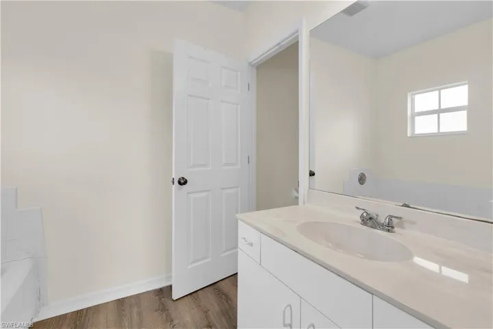 Full bath featuring vanity, dark wood-type flooring, and a bath