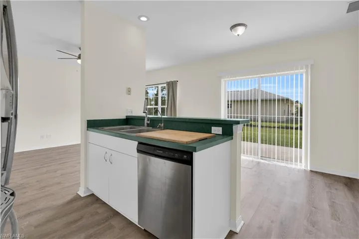 Kitchen with white cabinetry, dishwasher, dark countertops, light wood finished floors, and recessed lighting