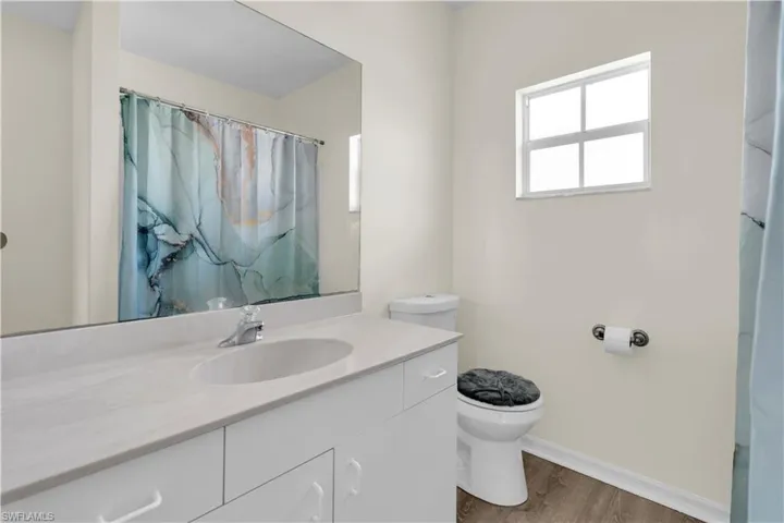 Full bath with vanity, light wood-style floors, and a shower with shower curtain
