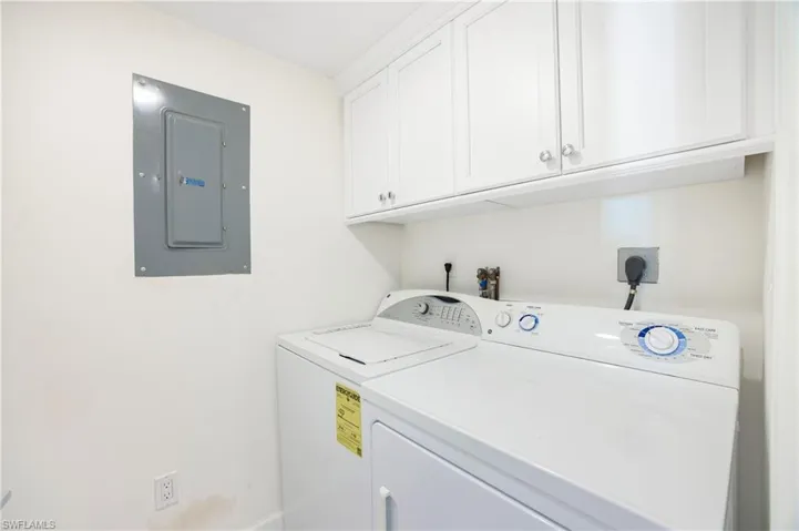 Washroom with electric panel, cabinet space, and washer and dryer