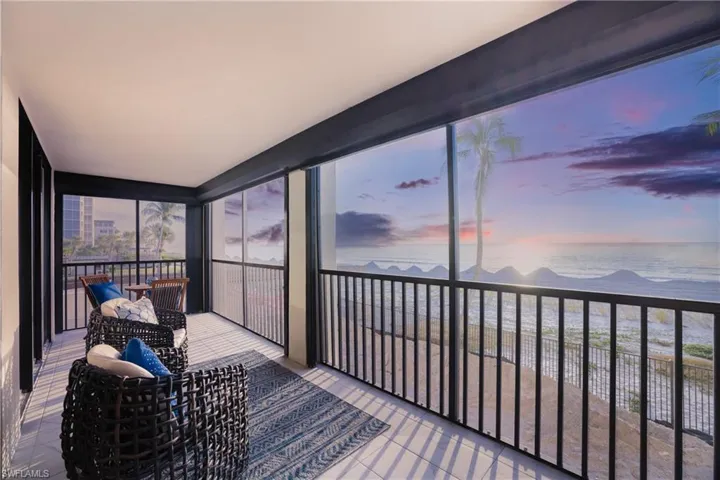 Sunroom featuring view of water and beach and expansive windows