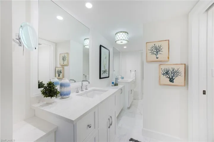 Full bath featuring two vanities, light marble finish floors, and recessed lighting