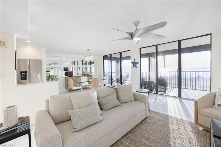Living area with ceiling fan, tile patterned floors, and a wall of windows