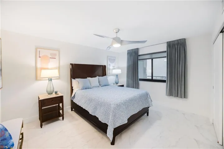 Bedroom with a closet, marble look tile flooring, and ceiling fan