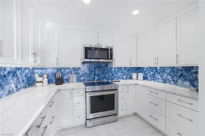 Kitchen featuring appliances with stainless steel finishes, white cabinets, light stone countertops, and recessed lighting