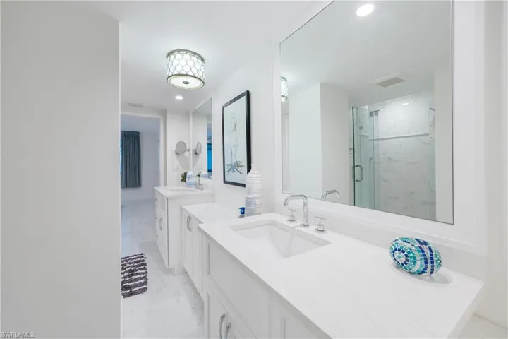 Full bathroom with light marble finish floors, two vanities, a marble finish shower, and recessed lighting