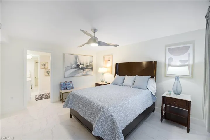Bedroom with a ceiling fan and light marble finish floors