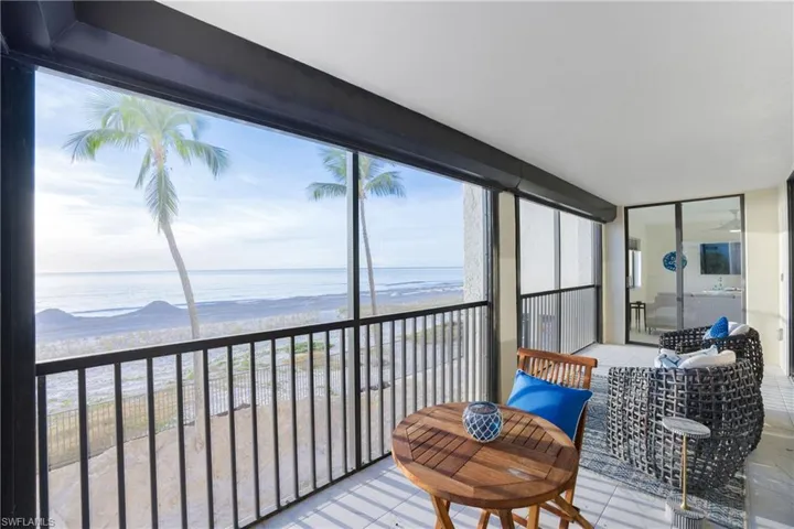 Sunroom / solarium featuring view of water and beach and expansive windows