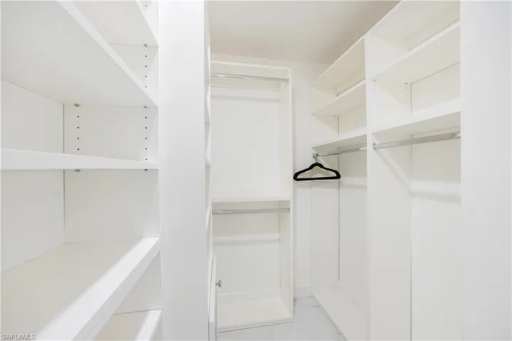 Walk in closet featuring light marble finish flooring