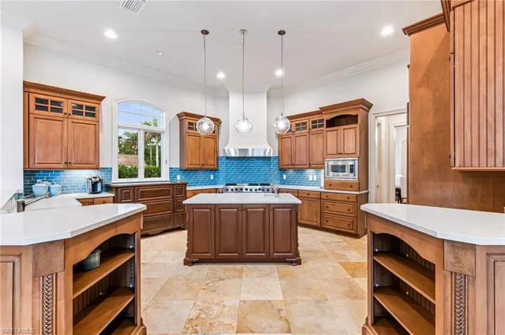 Kitchen with pendant lighting, a center island, stainless steel appliances, and tasteful backsplash