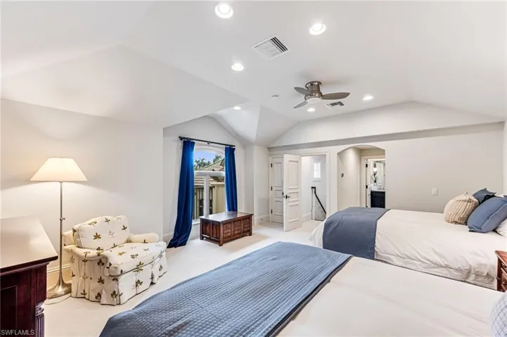 Carpeted bedroom with ceiling fan and lofted ceiling