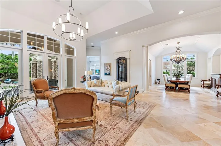 Living room featuring lofted ceiling, ornate columns, french doors, and a chandelier