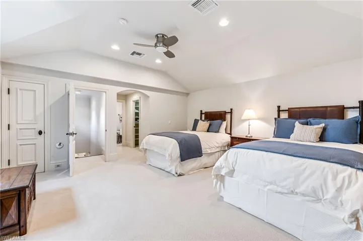 Bedroom featuring light colored carpet, vaulted ceiling, and ceiling fan