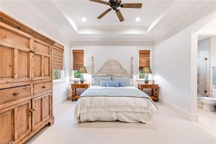 Bedroom featuring ensuite bath, ceiling fan, light colored carpet, and ornamental molding