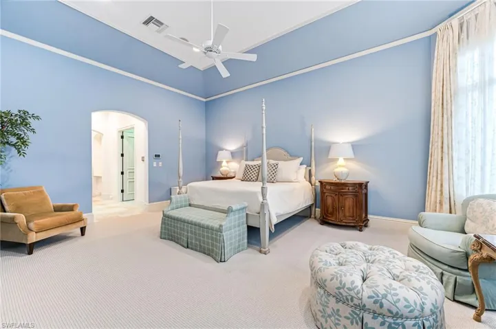 Bedroom featuring multiple windows, ceiling fan, light carpet, and a high ceiling