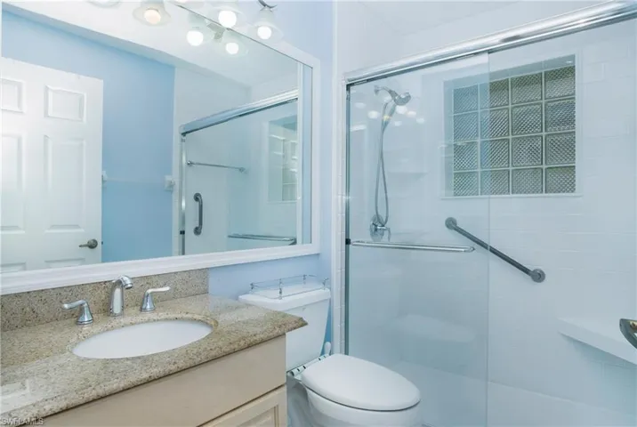 Bathroom featuring walk in shower, toilet, and large vanity