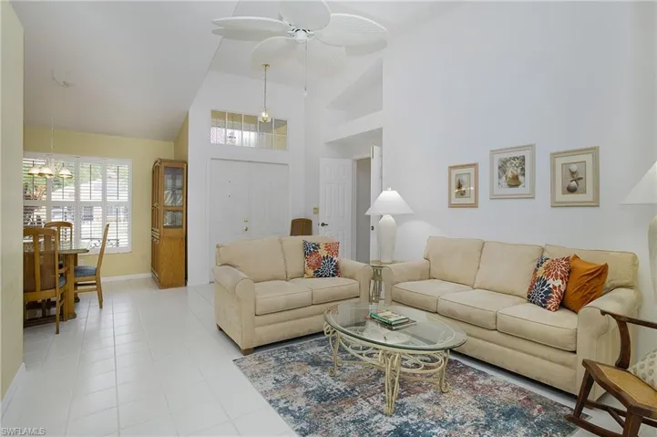 Living room with a towering ceiling, ceiling fan, and light tile flooring