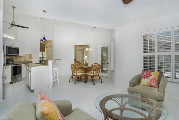 Tiled den room with ceiling fan off kitchen