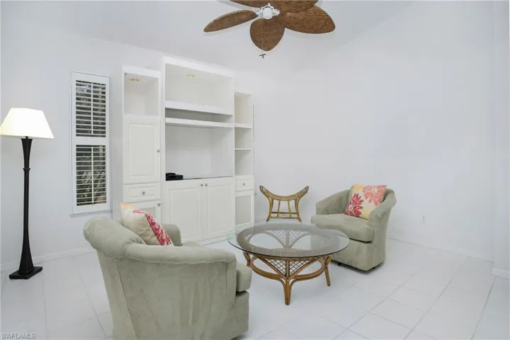 Den area featuring built in shelves, ceiling fan, and light tile floors