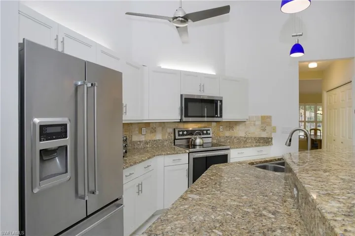 Kitchen featuring appliances with stainless steel finishes, sink, tasteful backsplash, ceiling fan, and light tile floors