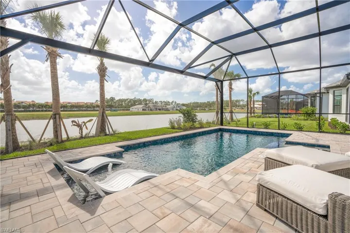 Outdoor pool with a water view, a lanai, a patio, a sunroom, and a lawn