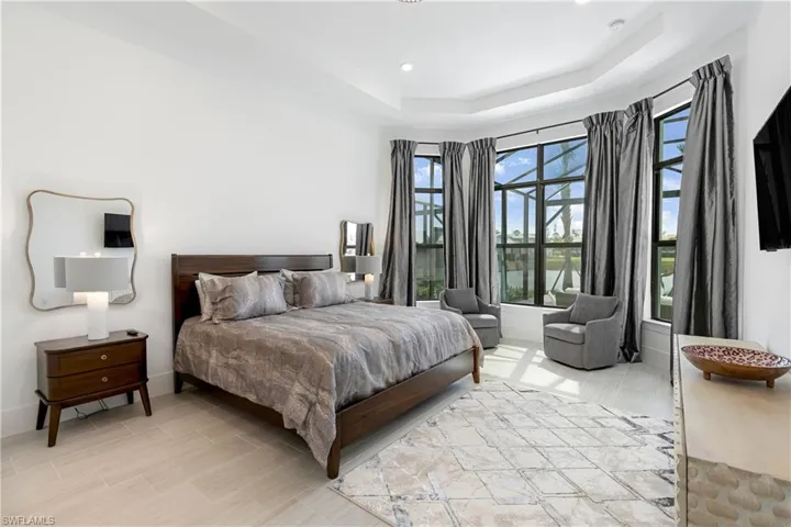 Bedroom with a raised ceiling, recessed lighting, and wood finish floors