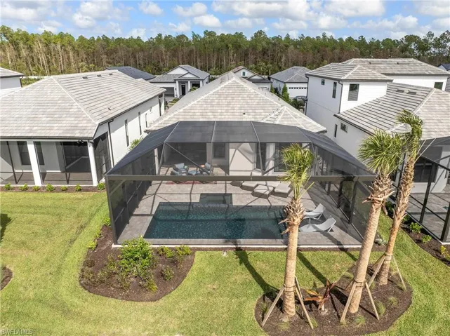 Rear view of house featuring an outdoor pool, a lanai, a sunroom, and a yard