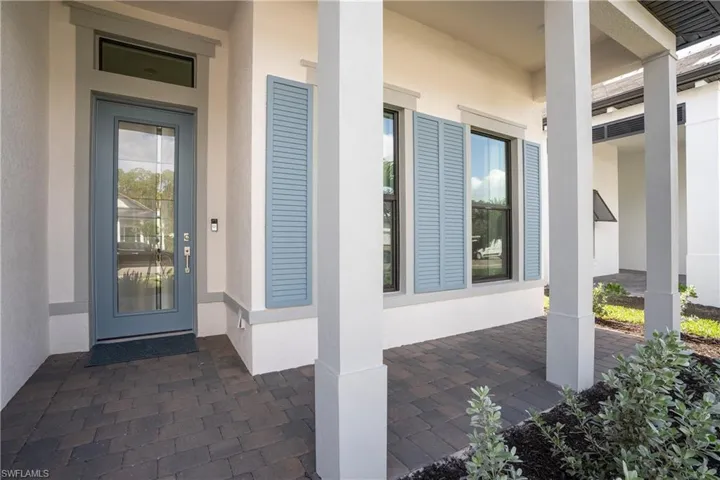 Doorway to property with covered porch and stucco siding