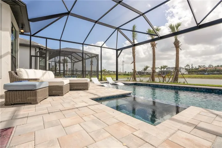 Outdoor pool featuring a lanai, a sunroom, a patio area, a hot tub, and a water view
