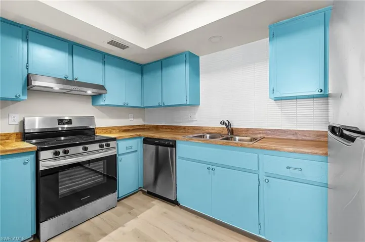 Refreshed kitchen w/tropical Key West Blue cabinets, 'butcher block' countertops, modern tile backsplash, and stainless steel appliances.