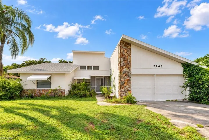 Mid-century modern facade with stone accents, a two-car garage, and a screened entry