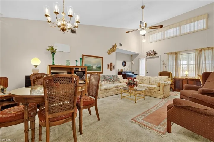 Vaulted ceiling, ceiling fan, wall-mounted light fixture, upper transom windows, and an arched entryway