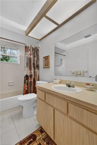 Wood-finish vanity with an integrated sink, large wall-mounted mirror, and tile flooring