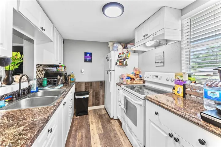 Kitchen with white cabinets, dark wood-type flooring, white electric stove, and sink
