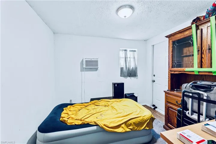 Bedroom featuring an AC wall unit and a textured ceiling