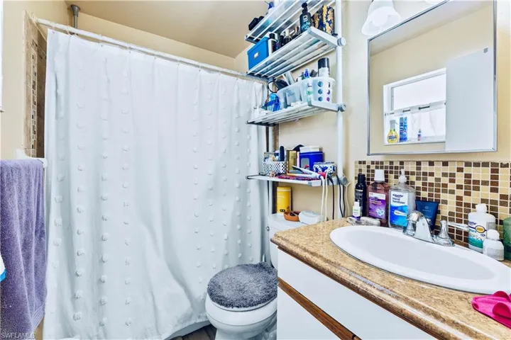 Bathroom featuring vanity, toilet, and backsplash