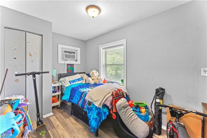 Bedroom with a wall mounted air conditioner and wood-type flooring