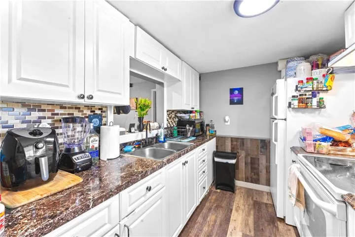 Kitchen with white cabinets, sink, backsplash, white range with electric stovetop, and dark hardwood / wood-style floors