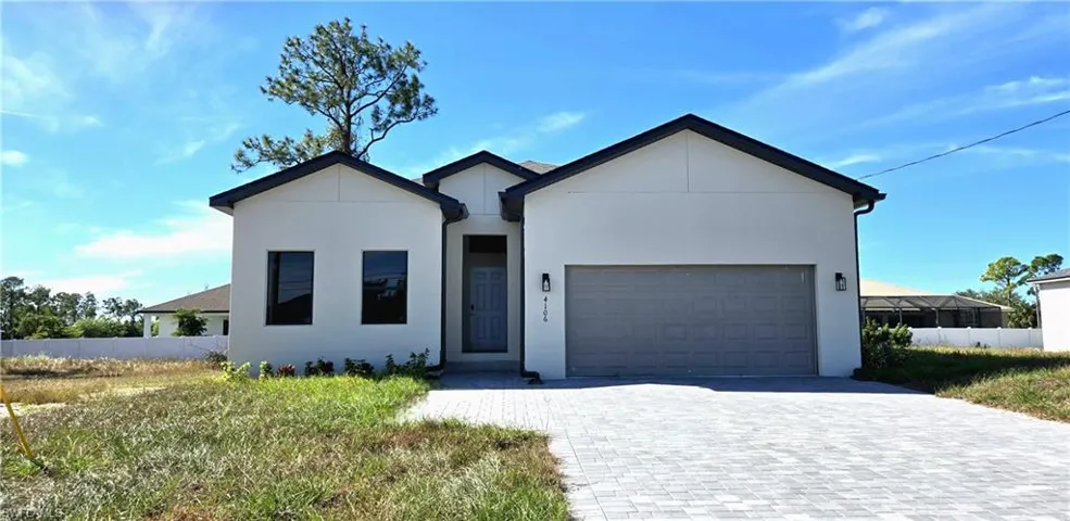 View of front facade with decorative driveway, stucco siding, and an attached garage