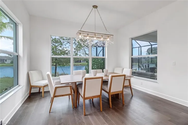 Dining room with a water view, dark wood-style floors, and a chandelier